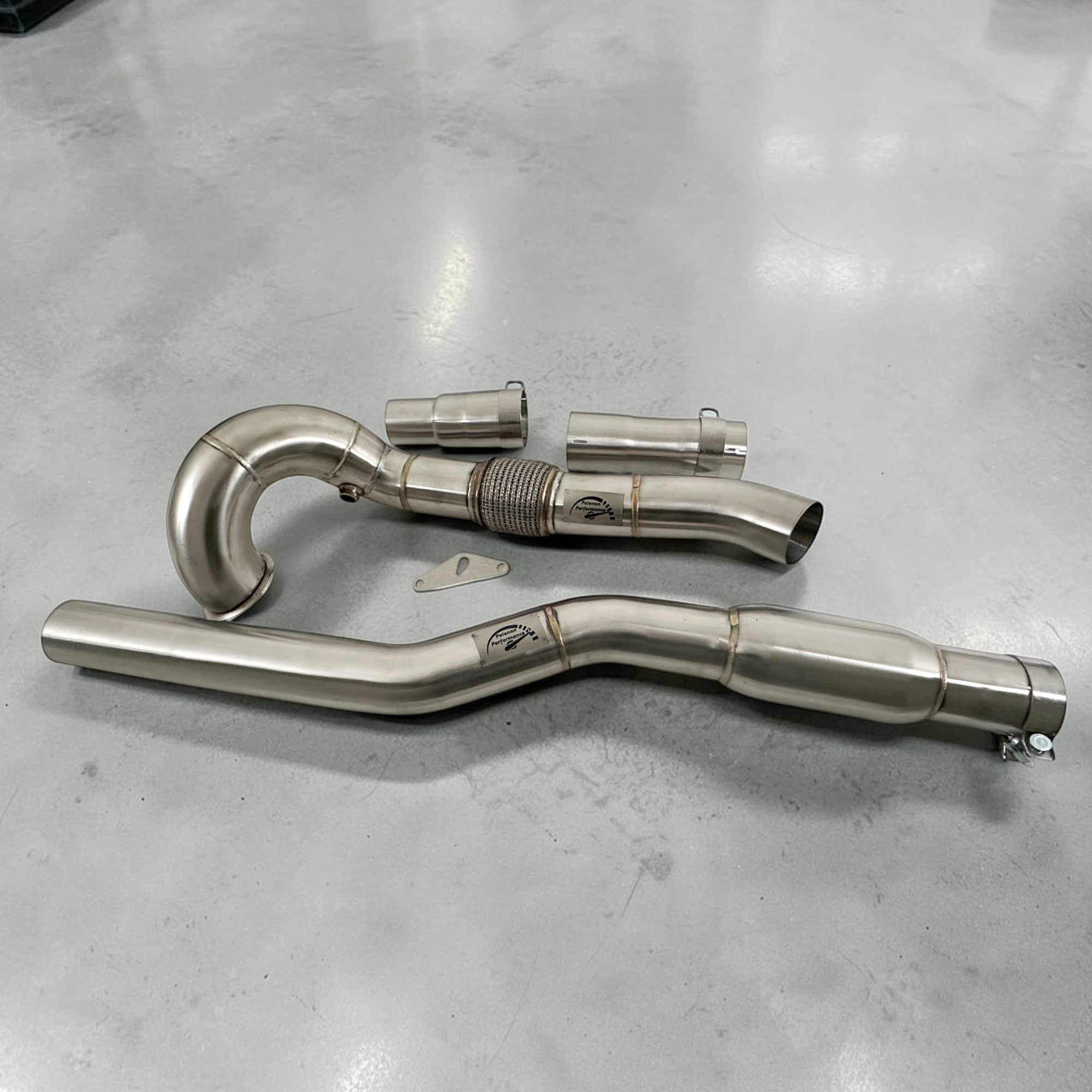 Racing Downpipe For VW MK7 Golf R 2.0T Audi S3 A3 8V AWD on a gray surface
